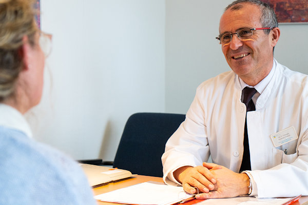 Gespräch von Rehabilitatandin und lächelndem Arzt im Kittel  Gespräch von Rehabilitatandin und lächelndem Arzt im Kittel