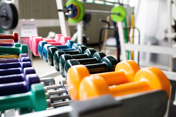 Farblich sortierte Hanteln aufgereiht im Trainingsraum Farblich sortierte Hanteln aufgereiht im Trainingsraum