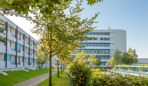 Rückseite der Klinik Wingertsberg mit Bäumen und Liegewiese 