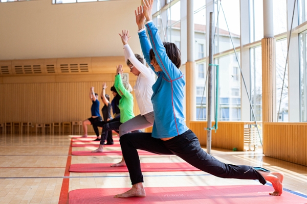 Yogagruppe in der lichtdurchfluteten Sporthalle  Yogagruppe in der lichtdurchfluteten Sporthalle